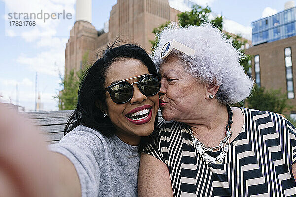 Ältere Frau küsst Tochter und macht Selfie