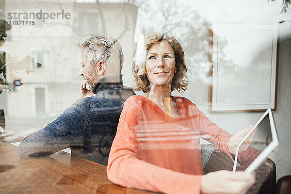 Frau hält Tablet-PC und sitzt neben Mann im Café