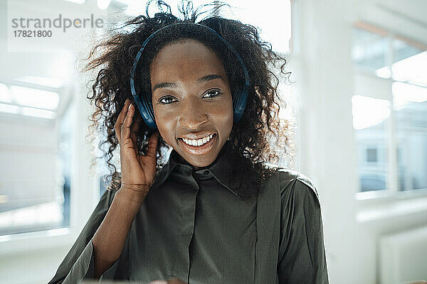 Lächelnde junge Frau  die über kabellose Kopfhörer Musik hört