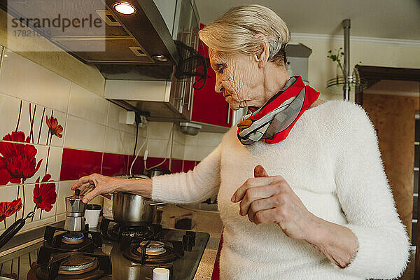 Ältere Frau bereitet zu Hause in der Küche Kaffee zu