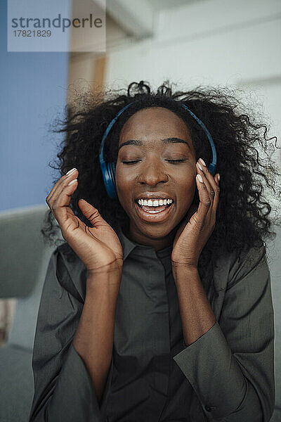Glückliche junge Frau  die Musik über kabellose Kopfhörer genießt