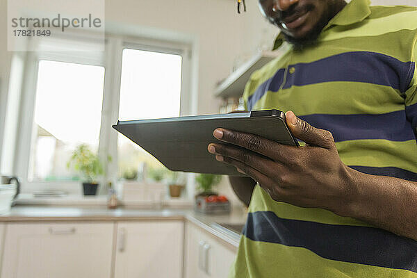 Hände eines Mannes mit Tablet-PC in der Küche
