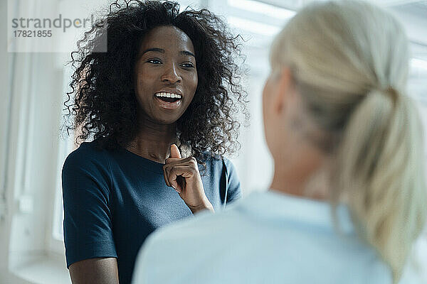 Happy businesswoman talking with colleague in office