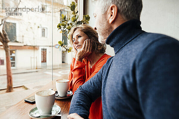 Mann schaut Frau an  die mit dem Kopf in den Händen im Café sitzt