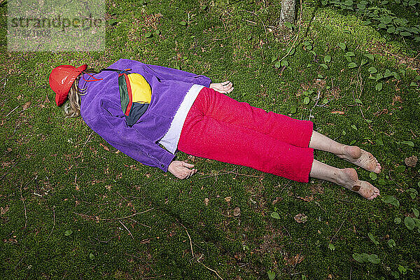 Woman with waist pack lying in forest