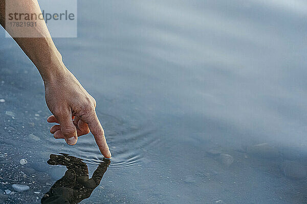 Hand of mature man touching water