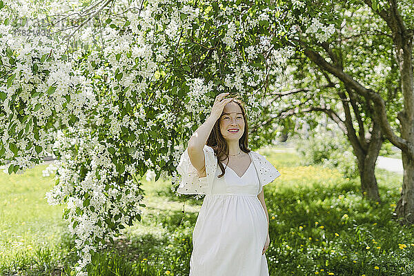 Glückliche schwangere Frau steht im Park