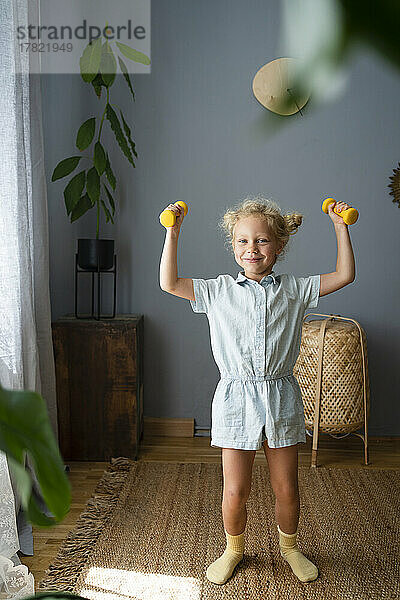 Girl holding dumbbells standing at home
