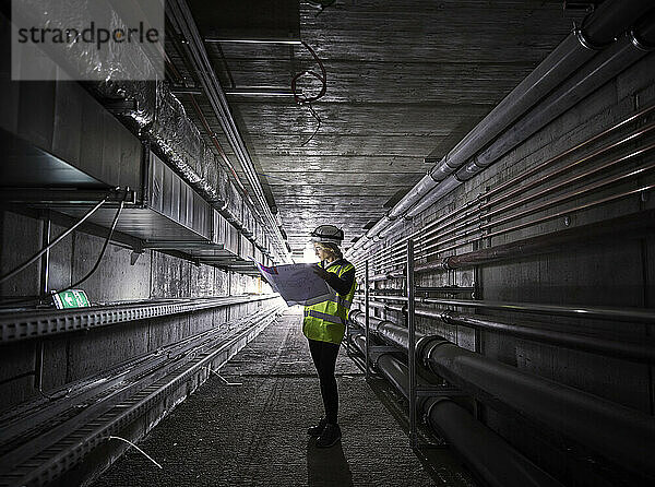 Junger Ingenieur betrachtet Bauplan im Tunnel