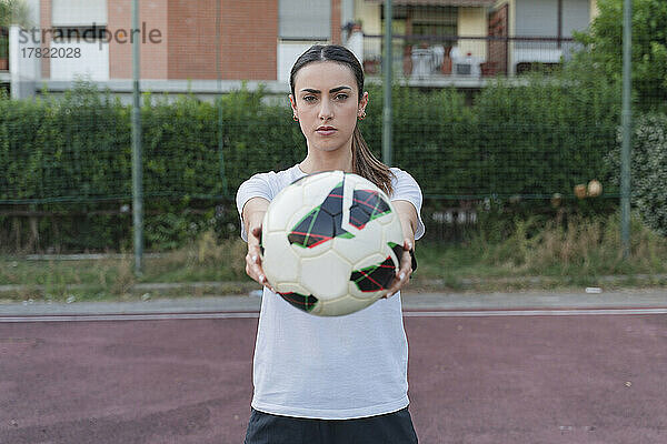 Selbstbewusste junge Frau zeigt den Ball im Fußballfeld