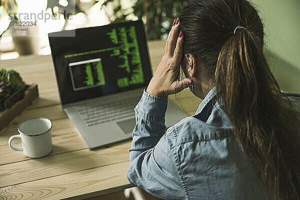 Müde Geschäftsfrau sitzt im Heimbüro vor dem Laptop