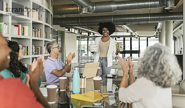 Zufriedene Geschäftskollegen applaudieren der Geschäftsfrau mit Lunchboxen im Büro