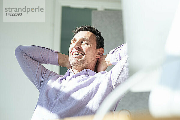 Carefree businessman with hands behind head relaxing at office