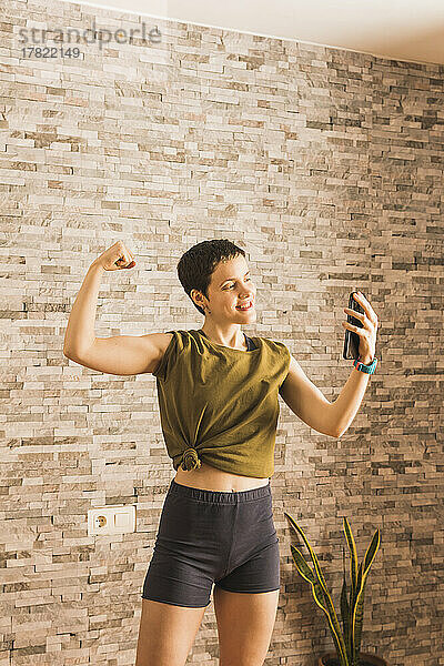 Glückliche Frau  die Muskeln spielen lässt und ein Selfie mit dem Smartphone macht