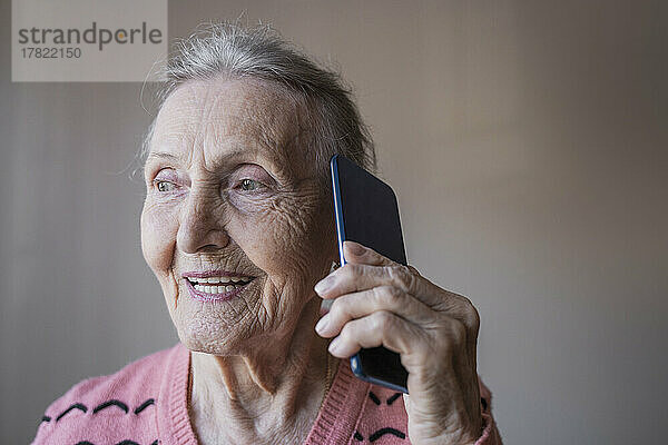 Glückliche ältere Frau  die auf dem Smartphone spricht