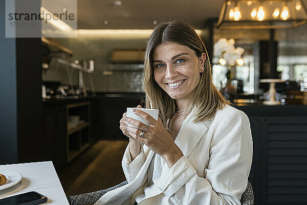 Lächelnde Geschäftsfrau hält Kaffeetasse im Restaurant