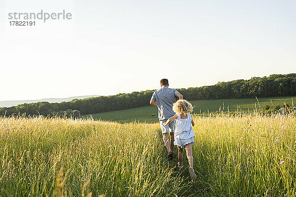 Vater und Tochter laufen gemeinsam im Feld