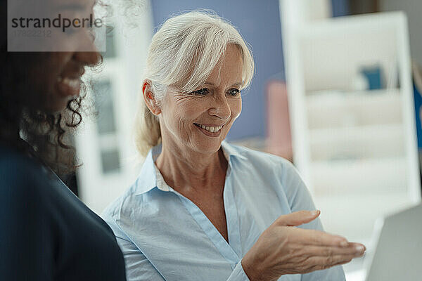 Smiling senior businesswoman talking with colleague in office