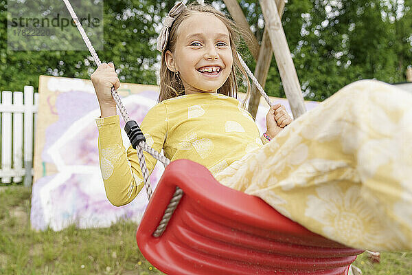 Smiling girl swinging on swing at playground