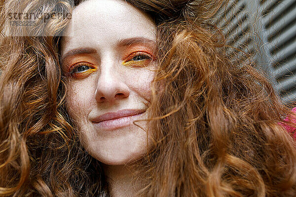 Lächelnde rothaarige Frau mit orangefarbenem Lidschatten-Make-up