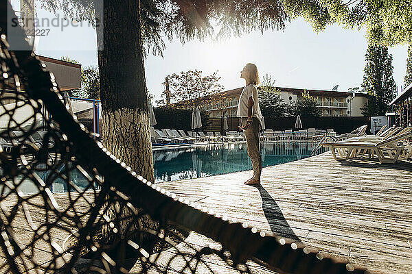 Frau steht an einem sonnigen Tag im Resort am Pool