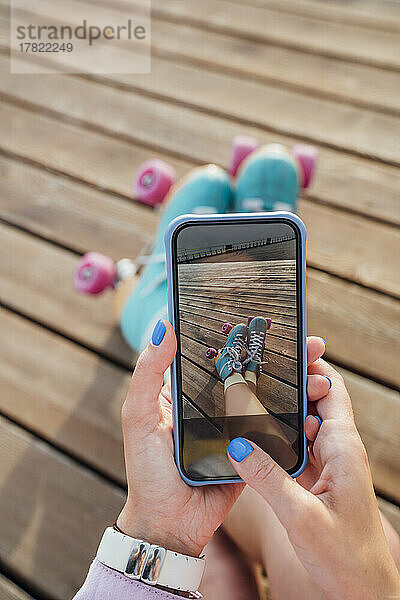 Hände einer Frau  die Rollschuhe per Smartphone fotografiert