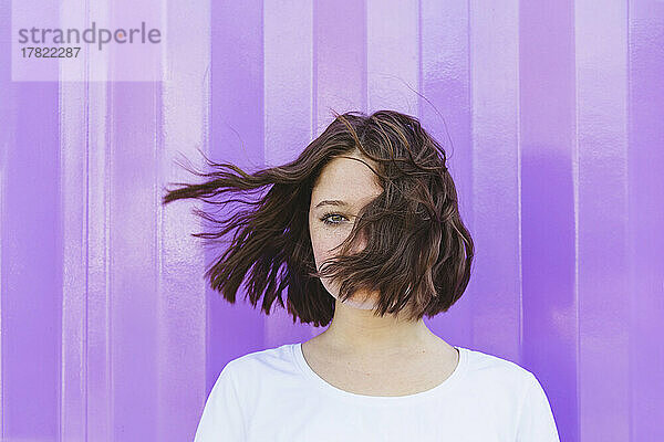 Teenage girl with tousled hair in front of purple cargo container