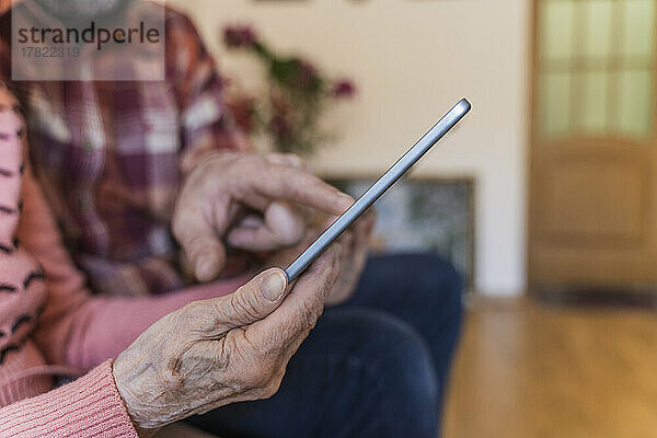 Reifer Mann bringt Seniorin im Wohnzimmer Tablet-PC bei