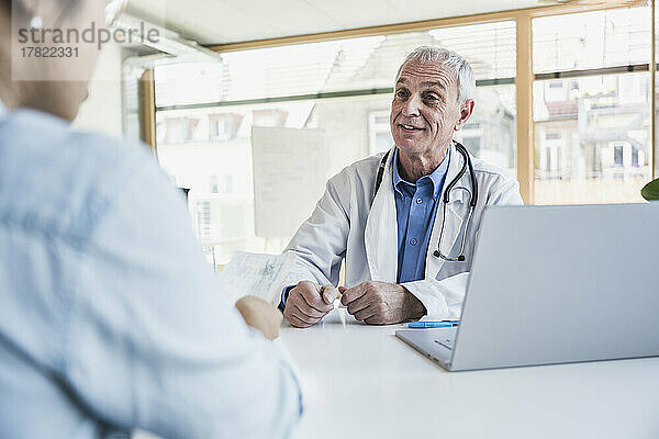 Happy senior doctor discussing with patient at hospital