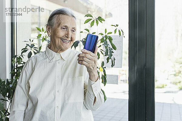 Glückliche Seniorin spricht per Videoanruf im Café