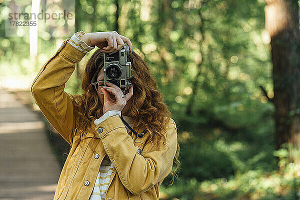 Frau fotografiert mit der Kamera im Wald