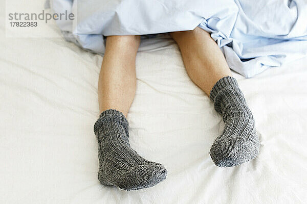 Frau mit Socken zu Hause im Bett
