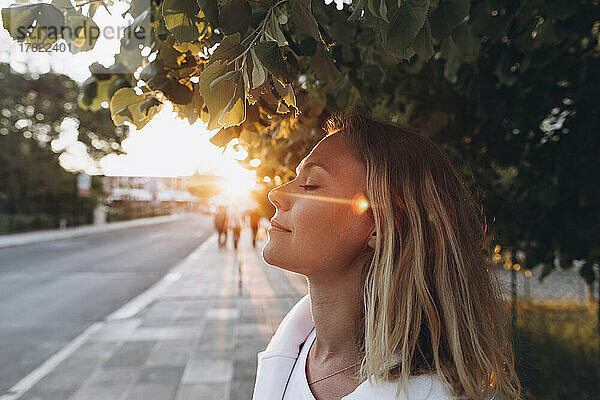 Lächelnde Frau mit geschlossenen Augen  die das Sonnenlicht genießt