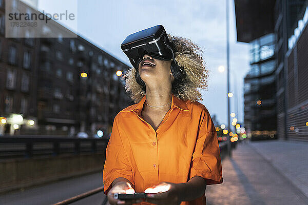 Frau schaut nachts mit einem Virtual-Reality-Headset nach oben und hält einen Controller in der Hand