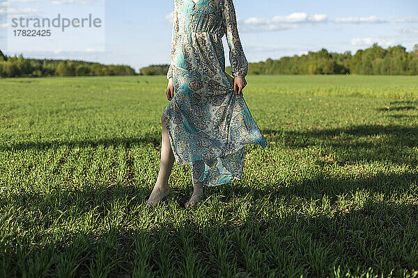 Frau steht an einem sonnigen Tag im Feld