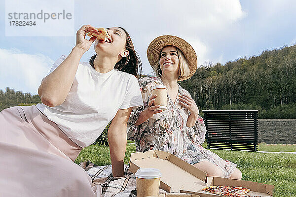 Frau isst am Wochenende Pizza von einem Freund im Park