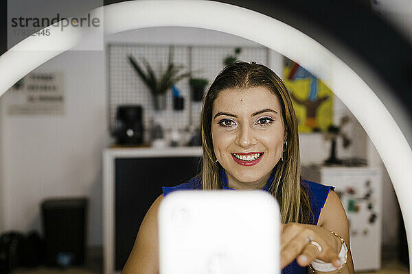 Lächelnde junge Geschäftsfrau  die im Büro vloggt