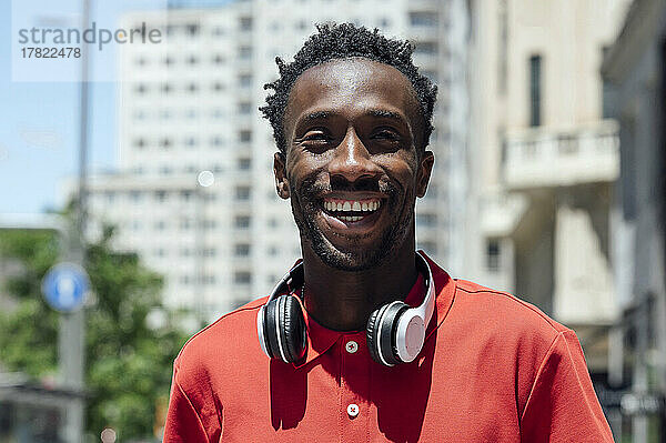 Glücklicher Mann mit kabellosen Kopfhörern an einem sonnigen Tag
