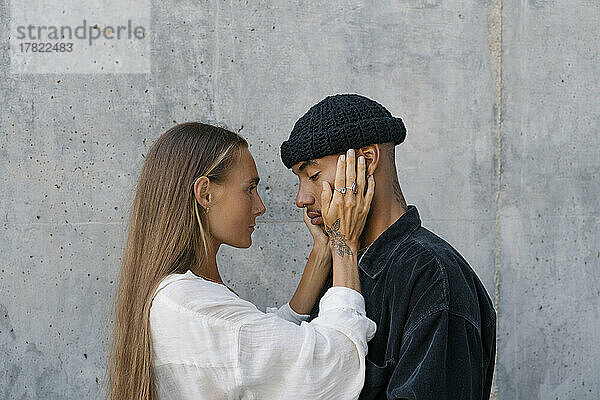 Woman embracing man standing in front of wall