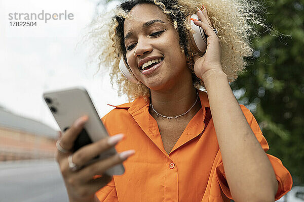 Glückliche Frau  die per Smartphone Musik über Kopfhörer hört