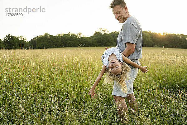 Lächelnder Vater trägt seine Tochter und genießt das Feld