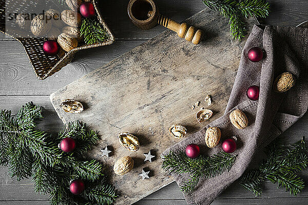 Studioaufnahme von Schneidebrett  sternförmigem Weidenkorb  Zweigen  Weihnachtsschmuck  Walnüssen und einfachem Nussknacker