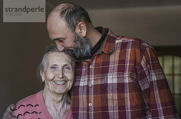 Mature man kissing senior woman at home