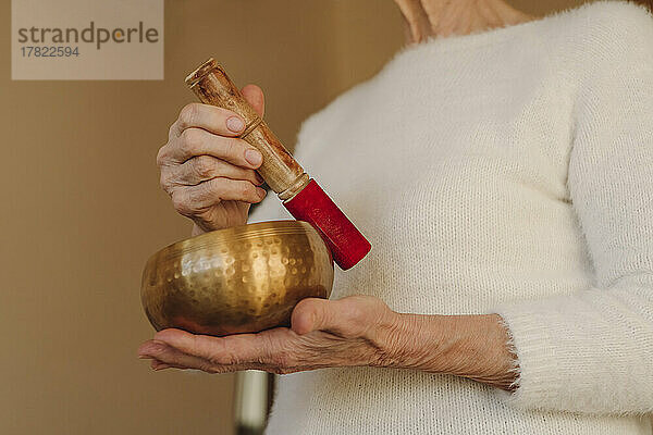 Hands of senior woman holding singing bowl