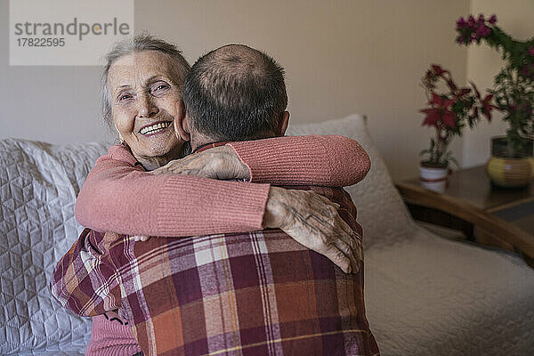 Happy senior woman hugging mature man at home