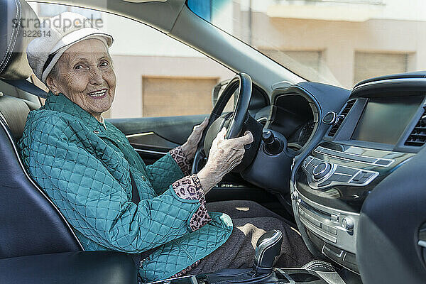 Glückliche ältere Frau sitzt auf dem Fahrersitz im Auto