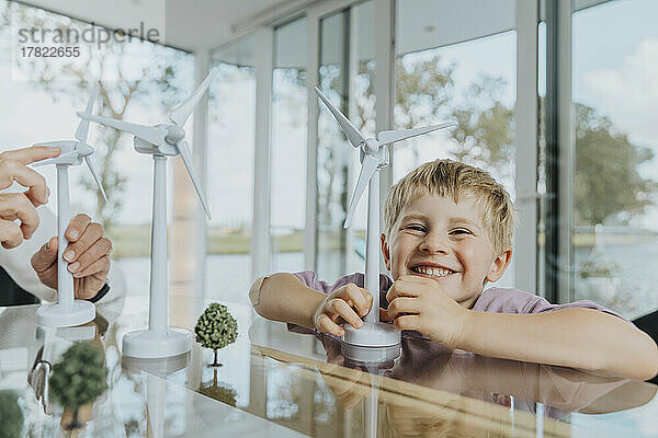 Glücklicher Junge mit Windturbinenmodell  der zu Hause sitzt
