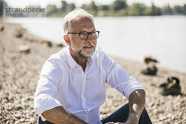 Älterer Mann mit Brille am Flussufer