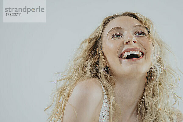 Happy young woman with blond hair against white background