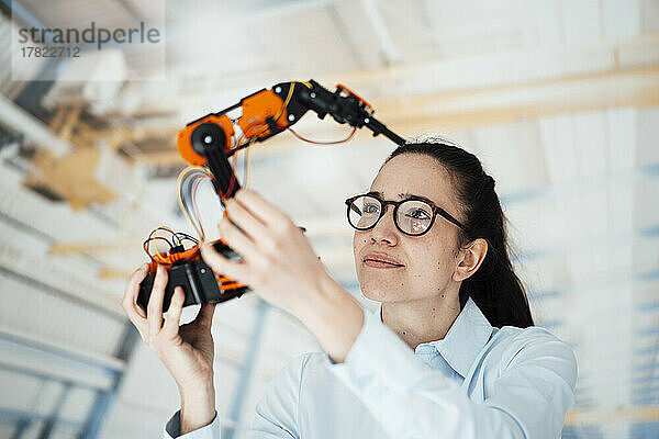 Geschäftsfrau analysiert Roboterarmmodell in Fabrik